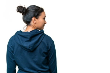 Young Uruguayan woman over isolated chroma key background in back position and looking side