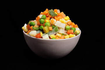 Mexican mix of frozen vegetable in a plastic bowl on a black background