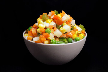 Mexican mix of frozen vegetable in a plastic bowl on a black background