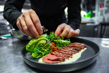 chef hand preparing Roastbeef salad with vegetables on restaurant kitchen