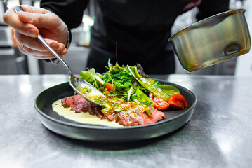 chef hand preparing Roastbeef salad with vegetables on restaurant kitchen