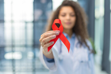 Woman doctor holding a red ribbon in her hand an international day of protecting people from cancer...