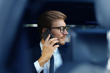 Thoughtful confident businessman talking on the phone while sitting in the car.
