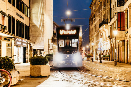 Munich, Germany, a MVG streetcar/tram goes through the old town past nice stores at night with lots of lighting, November 13, 2022