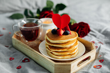 Homemade pancakes with berries, cup of tea and flowers and gift box. Breakfast or brunch for Valentine's Day.