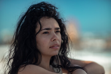 Sea woman rest. Portrait of a woman with long curly black hair in a beige dress stands on a balcony against the backdrop of the sea. Tourist trip to the sea.