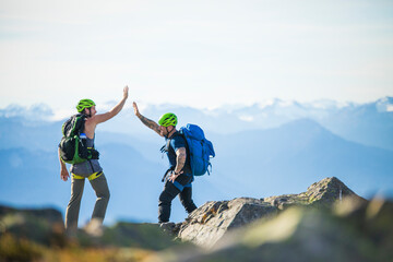 Two climbers hi-five on mountain summit of Douglas Peak, B.C., Canada.