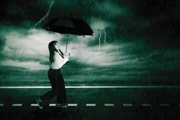 Cheerful businesswoman holding umbrella under the rain