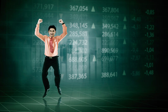 Happy stock broker jumping with trading numbers background