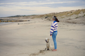Middle-aged brunette woman on the empty beach with her labrador retriever dog