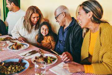 Happy latin family having fun eating together home - Focus on kid face - Lifestyle moments with parents and grandparents concept