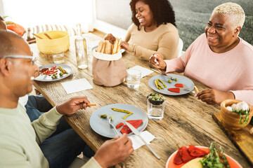 Happy african family eating lunch together at home - Soft focus on mother right hand