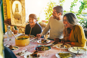 Happy latin family having fun eating together during home dinner - Soft focus on father hands