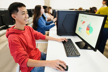 Young students using computers inside technology class at school room - Focus on asian guy eye