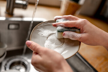 Girl washing dishes at kitchen at home - Powered by Adobe