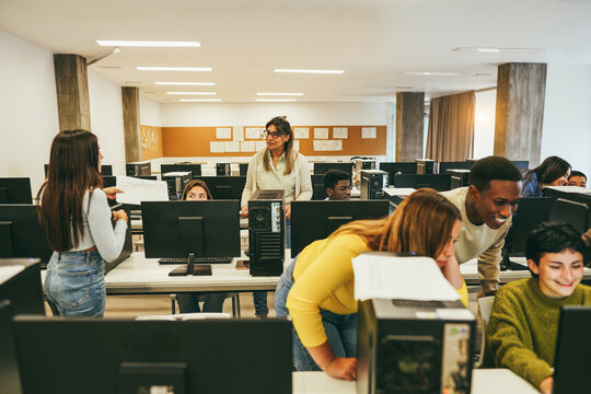 Teacher working with students inside computer class college room - Focus on mature woman face