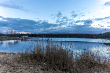 A beautiful little lake called Oberwaldsee during blue hour in Germany at a sunny day in Autumn with a colorful forest reflecting in the water.