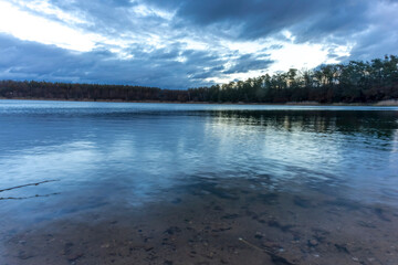 A beautiful little lake called Oberwaldsee during blue hour in Germany at a sunny day in Autumn with a colorful forest reflecting in the water.