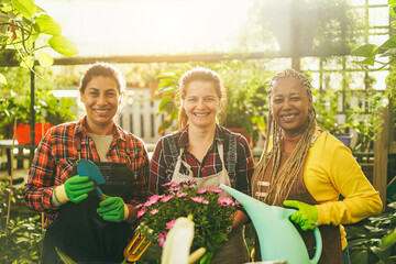 Multiracial senior women working inside greenhouse garden - Soft focus on center female face