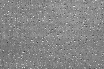 Grey glass window with droplets of water from rain to be used as a textured background