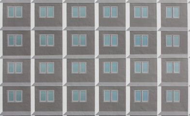 Minimalist facade of modern office building with square Windows.  Frontal view of the facade of building with a lot of windows with people staying at home during quarantine.