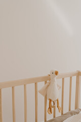 Fototapeta na wymiar Children's toy duck on crib. Baby minimal interior design decoration