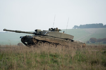 large tank crosses over a raised road from a field