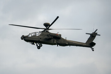 a dark coloured helicopter flying low to the ground 