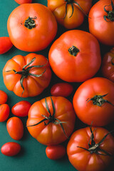 Fresh farm tomatoes (different types) on the green background, selective focus