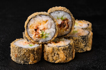 baked sushi rolls with ell on black concrete background