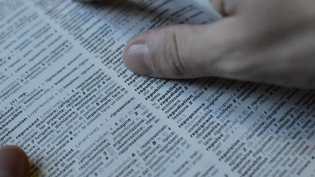 caucasian student's hand using english dictionary for language learning.