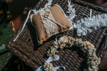 Boho wedding set on a rustic background: golden rings on pincushion, floral circlet and lace...