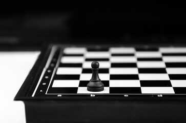 chess piece black pawn stands on edge of chessboard. concept of achieving goals, leadership