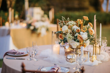 Beautiful outdoor wedding decoration in garden. Round tables decorated with flowers, candles and...
