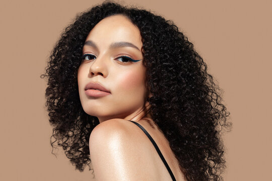 Beautiful young woman on beige background. Natural makeup, glowing dark skin