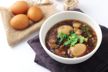 Egg and Pork in Sweet Brown Sauce served in a white cup. In restaurants in Thailand, stewed eggs are a popular dish in Thai people.