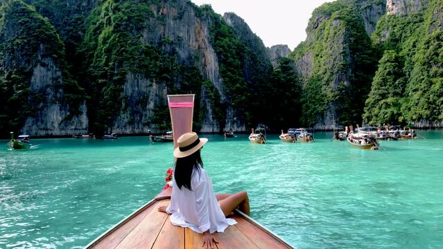 Asian Thai women in front of a longtail boat at Koh Phi Phi Island Thailand, Pileh Lagoon.