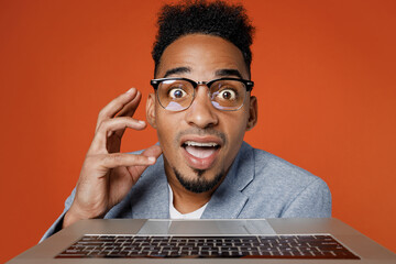 Young amazed employee business man corporate lawyer wear classic formal grey suit shirt glasses work in office typing on close up pc computer keyboard isolated on plain red orange background studio.