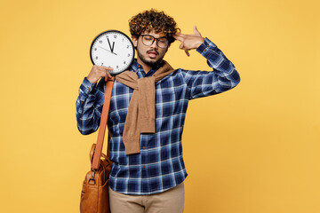 Young teen Indian boy IT student wear casual clothes shirt bag hold clock, point fingers to head as...