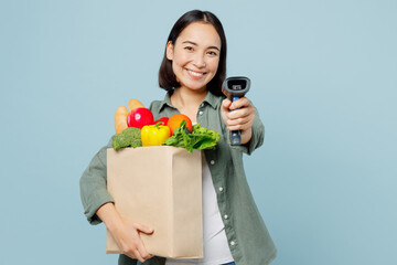 Fototapeta na wymiar Young woman wears casual clothes hold brown paper bag scanning food products check bar code put scan camera on you isolated on plain blue background studio. Delivery service from shop or restaurant.