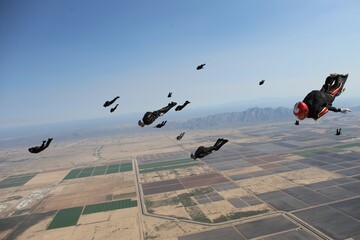 Skydivers tracking from a skydive in Arizona with mountain range in the background.