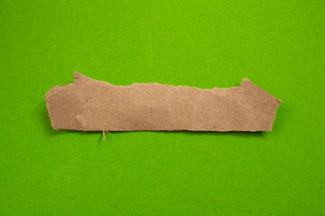 Blank torn cardboard isolated on green background. Top view of carton piece with copy space.