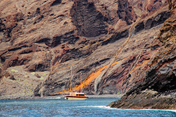 Pleasure yacht in the bay near colorful picturesque rocky shores