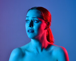 Head and shoulders close up portrait of pretty girl with expressive facial expressions, with  colourful neon gel lighting, isolated on studio background.