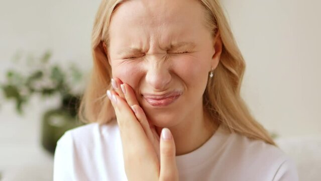 Woman with a toothache, touching her face. The concept of dental disease. Tooth pain due to caries	