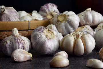 Close-up shot of garlic laying on black stone table and bamboo baskets In the dimly lit kitchen prepared for the ingredients of the meal.