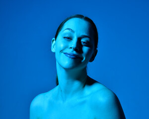 Head and shoulders close up portrait of pretty girl with expressive facial expressions, with  colourful neon gel lighting, isolated on studio background.