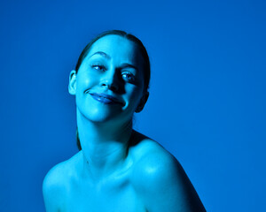 Head and shoulders close up portrait of pretty girl with expressive facial expressions, with  colourful neon gel lighting, isolated on studio background.