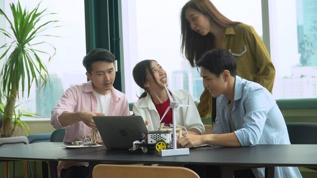 group of asian young university students brainstorming and discussion with laptop computer  in college library  science and technology subject  . clapping hand and congratulate to success in office