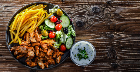 Kebab served with french fries, vegetable salad and tzatziki